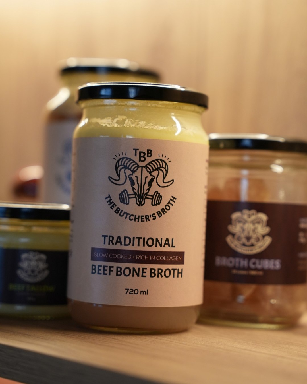 720 ml jar of The Butcher's Broth beef bone broth on a wooden shelf, with beef tallow and broth cubes beside it